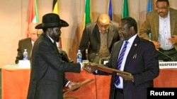 FILE - South Sudan's President Salva Kiir, left, and South Sudan's rebel commander Riek Machar exchange documents after signing a cease-fire agreement during an Inter Governmental Authority on Development (IGAD) Summit in Addis Ababa, Ethiopia.