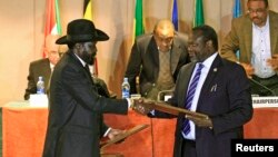FILE - South Sudan's President Salva Kiir (L) and rebel commander Riek Machar exchange documents after signing a cease-fire agreement in Ethiopia's capital Addis Ababa, Feb. 1, 2015.