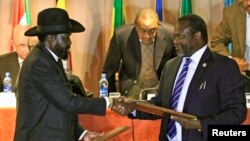 FILE - South Sudan's President Salva Kiir, left, and rebel commander Riek Machar exchange documents after signing a cease-fire agreement in Addis Ababa, Ethiopia, Feb. 1, 2015.