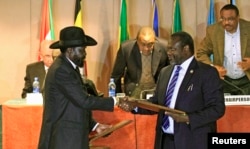 FILE - South Sudan's President Salva Kiir, left, and South Sudan rebel commander Riek Machar exchange documents after signing a cease-fire agreement during the Inter Governmental Authority on Development (IGAD) Summit on the case of South Sudan in Ethiopia.