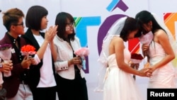 FILE - Newly married same-sex couple Tran Ngoc Diem Hang (R) and Le Thuy Linh (2nd R) share a moment during their public wedding as part of a lesbian, gay, bisexual, and transgender event on a street in Hanoi, October 27, 2013. 