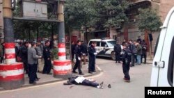 A body is pictured lying on the ground at a crime scene on a street, in Changsha, Hunan Province March 14, 2014. 