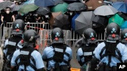 2019年6月12日在香港立法會附近，帶有防暴裝備的警察同打著雨傘的示威者對峙。