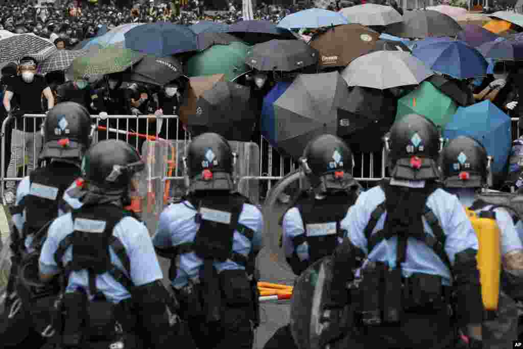 2019年6月12日在香港立法會附近，帶有防暴裝備的警察與打著雨傘的示威者對峙。