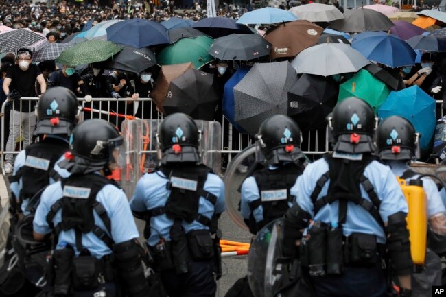 2019年6月12日在香港立法会附近，带有防暴装备的警察同打着雨伞的示威者对峙。