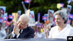 Former Cambodian King Norodom Sihanouk and Queen Norodom Monineath Sihanouk are greeted by students along a Phnom Penh road during during the marking of the country's 50th Independence Day in 2003.