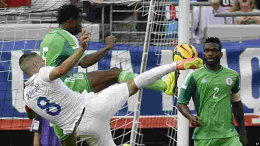 United States's Clint Dempsey takes a shot on goal as he is defended by Nigeria's Efe Ambrose.