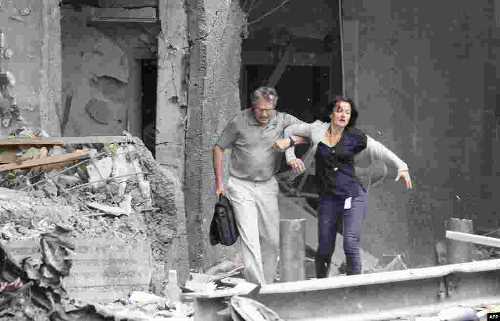 An injured woman is helped by a man at the scene of a powerful explosion that rocked central Oslo July 22, 2011. A huge explosion damaged government buildings in central Oslo on Friday including Prime Minister Jens Stoltenberg's office, injuring several p