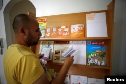 A Palestinian man check voting pamphlets in the office of the Central Elections Commission in the West Bank town of El Bireh, Aug. 17, 2016.