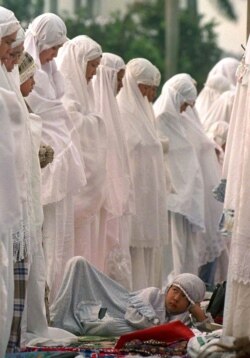 Ilustrasi. Seorang gadis muda bersandar ketika ribuan wanita Muslim Indonesia, termasuk ibunya, melakukan salat Idul Fitri di sebuah lapangan di luar masjid Al-Azhar di Jakarta Selatan. (Foto: Reuters)