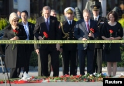 Turkish President Recep Tayyip Erdogan, second from left, and his wife, Emine Erdogan, left, hold carnations during a commemoration for the victims of Saturday's bombings in Ankara, Oct. 14, 2015.