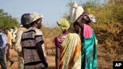 FILE - Women and girls speak to members of a U.N. peacekeeping patrol as they walk to get food in Bentiu, fearful of being attacked on the way, near Nhialdu, South Sudan, Dec. 7, 2018.