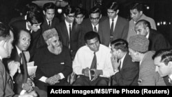 FILE - Muhammad Ali speaks to Muslims holding a book called "Towards Understanding Islam" written by Sayyid Abul Ala Maududi in London, Britain, May 1966. Ali died late Friday in Phoenix, Arizona, June 3, 2016.