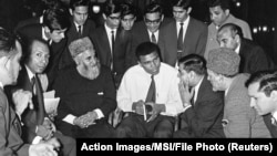 FILE - Muhammad Ali speaks to Muslims holding a book called "Towards Understanding Islam" written by Sayyid Abul Ala Maududi in London, May 1966. Ali died in Phoenix, Arizona, June 3, 2016.