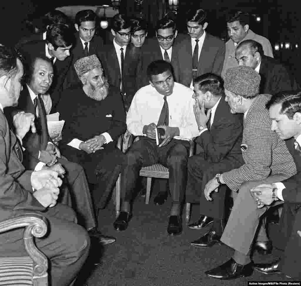 Muhammad Ali nói chuyện với các tín đồ Hồi giáo cầm một cuốn sách có tựa đề &quot;Để hiểu đạo Hồi&quot; của tác giả Sayyid Abul Ala Maududi tại London, Anh, vào tháng Năm 1966.