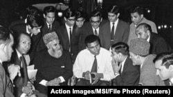 FILE - Muhammad Ali speaks to Muslims holding a book called "Towards Understanding Islam" written by Sayyid Abul Ala Maududi in London, Britain, May 1966. Ali died late Friday in Phoenix, Arizona, June 3, 2016.