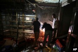 Abelino Vieira, center, covers the hole where looters entered his grocery and liquor store during a protest Tuesday night in Caracas, Venezuela, April 12, 2017.