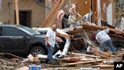 Joe Curry, left, and his friend search the damaged remains of his home.