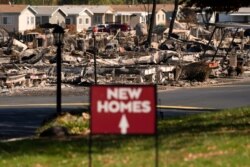 FILE - A sign advertising new homes stands in a neighborhood severely damaged by wildfire in Medford, Oregon, Sept. 20, 2020.