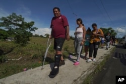 El migrante venezolano Jesús González, quien se rompió la pierna mientras cruzaba la selva del Darién, camina con su familia, que forma parte de una caravana migrante que se detuvo a descansar en Huixtla, estado de Chiapas, México, el miércoles 8 de junio de 2022. Foto AP.