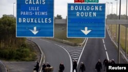 French riot policemen cross the Eurotunnel ramp for trucks after they pushed back migrants who were blocking the road early in the morning, at Coquelles near Calais, France, Aug. 2, 2015. 