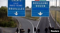 Des policiers anti-émeutes ayant repoussé des migrants qui bloquaient la route à Coquelles près de Calais, en France, le 2 août 2015 (REUTERS/Pascal Rossignol)