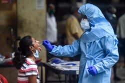 Seorang petugas kesehatan (kanan) mengambil sampel swab dari seorang penduduk di Mumbai, India, 16 Juli 2020. (Foto oleh Punit PARANJPE / AFP)