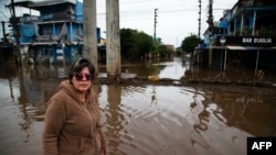 FILE - Orioplina Bechiln, a street barbecue vendor, walks along a flooded street around the Arena do Gremio stadium in Porto Alegre, Rio Grande do Sul State, Brazil, on May 29, 2024.