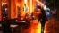 FILE - A woman passes empty tables before the late-night curfew due to restrictions against the spread of COVID-19 takes effect, in Berlin, Germany, Oct. 14, 2020.