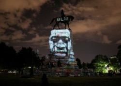 Artist Dustin Klein projects an image of George Floyd onto the statue of Confederate General Robert E. Lee in Richmond, Virginia, June 18, 2020.