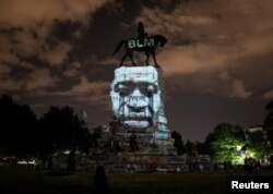 Artist Dustin Klein projects an image of George Floyd onto the statue of Confederate General Robert E. Lee in Richmond, Virginia, June 18, 2020.
