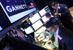 FILE - A specialist works at the post that handles Gannett on the floor of the New York Stock Exchange, Aug. 5, 2014.