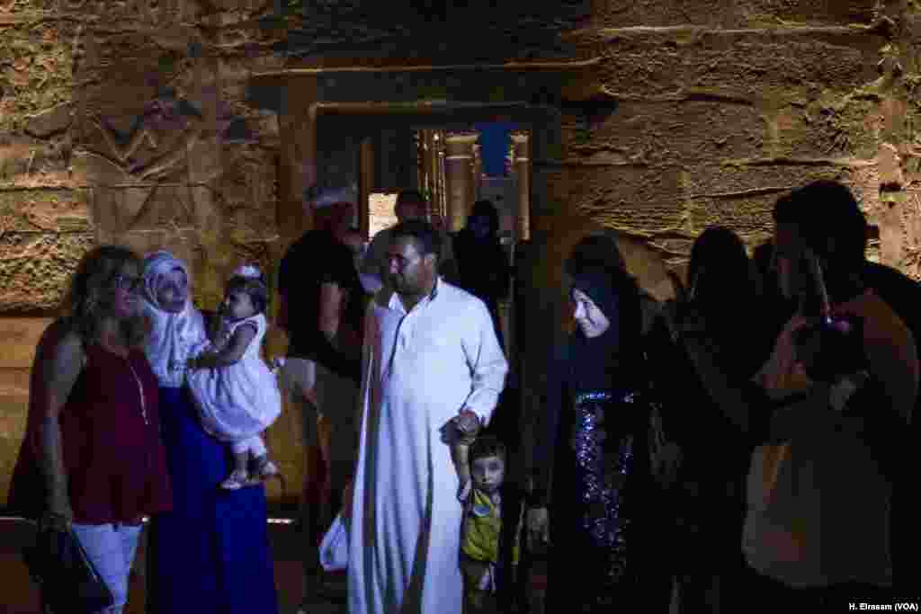 Seorang perempuan Mesir menggendong bayinya sedang berpose dengan seorang wisatawan di kuil Luxor, di Luxor, Mesir, 9 September 2017. (H. Elrasam/VOA)