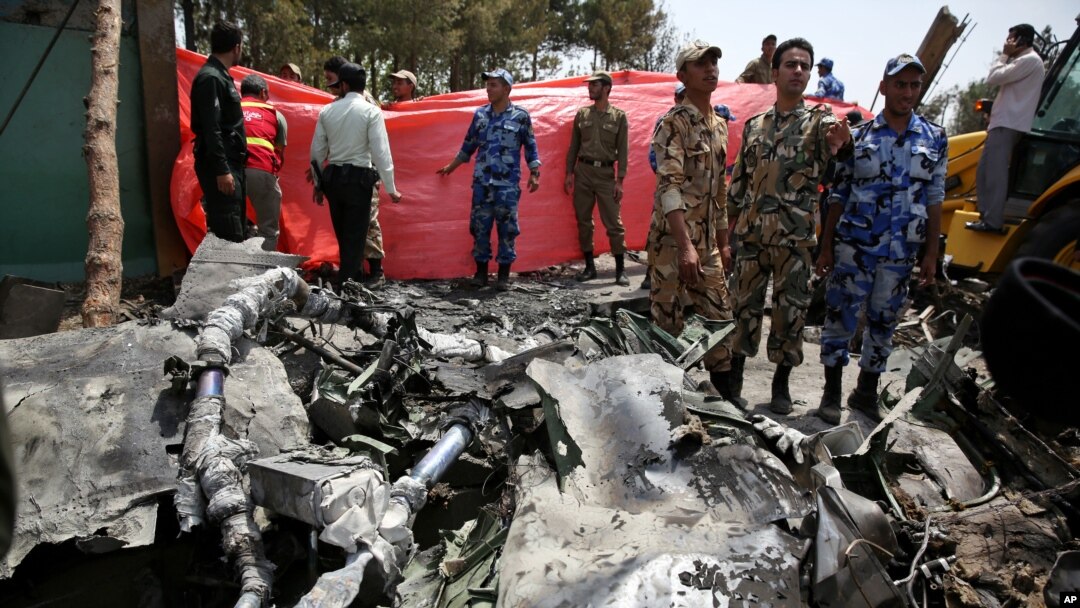 Anggota garda revolusi dan polisi Iran memeriksa lokasi kecelakaan pesawat Antonov-24 di Teheran, Iran (10/8).
