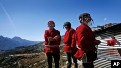 Umat Buddha suku dari daerah perbatasan India-Bhutan menyaksikan orang-orang mendekorasi kota dalam persiapan kedatangan pemimpin spiritual Tibet Dalai Lama di Tawang, di negara bagian Arunachal Pradesh, India timur laut, Sabtu, 7 November 2009. (AP Photo/Manish Swarup)