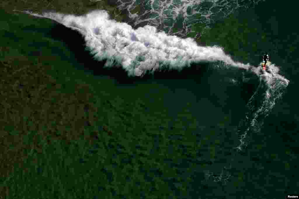 Seorang pria bermain selancar di pantai Barra da Tijuca di kota Rio de Janeiro, Brazil.