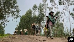 Un milicien armé non identifié croise des villageois qui s'enfuient avec quelques biens, près du village de Chenna Teklehaymanot, dans la région d'Amhara, au nord de l'Éthiopie, le 9 septembre 2021.