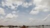 A Sudanese sits on a mound at a flooded field near the town of Osaylat, 60 km southeast of the capital in Khartoum, Sudan, Aug. 7, 2020.