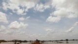 A Sudanese sits on a mound at a flooded field near the town of Osaylat, 60 km southeast of the capital in Khartoum, Sudan, Aug. 7, 2020.