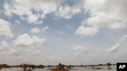 A Sudanese sits on a mound at a flooded field near the town of Osaylat, 60 km southeast of the capital in Khartoum, Sudan, Aug. 7, 2020.