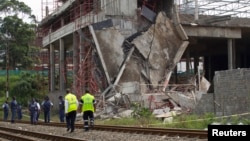 Policemen walk past a three-story building that collapsed in the South African town of Tongaat, about 28 miles north of Durban, Nov. 20, 2013.