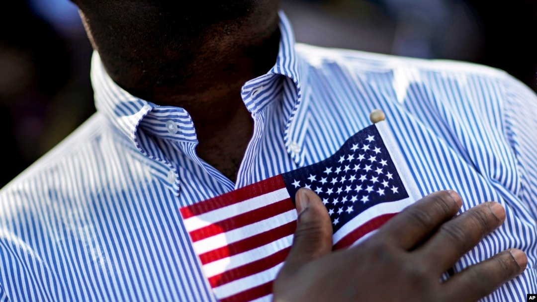 A candidate for citizenship holds the American flag at the start of a naturalization ceremony in Atlanta, Sept. 16, 2016. 