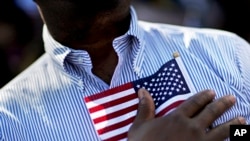 A candidate for citizenship holds the American flag at the start of a naturalization ceremony in Atlanta, Sept. 16, 2016. 