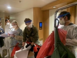 Medical personnel Guardian Angels with the 129th Rescue Wing, alongside individuals from the CDC don full personal protective equipment as they prepare to test travelers on the Grand Princess cruise ship for the coronavirus.