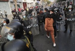 Agentes vestidos de civil detienen a una mujer durante las protestas tras el juicio político al presidente Martín Vizcarra, en Lima