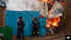 En esta foto divulgada por el gobernador de la región de Belgorod, en Rusia, se observa a trabajadores de emergencia junto a una casa incendiada después de un bombardeo ucraniano el 17 de marzo de 2024.