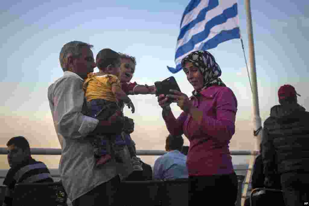 Refugees check their mobiles aboard a ferry traveling from the northeastern Greek island of Lesbos to the Athens&#39; port of Piraeus, Sept. 10, 2015. (AP)