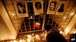 FILE- A man lights a candle at the National Stadium, that served as a detention center in the early years of the military dictatorship, during a vigil marking the 42nd anniversary of the military coup that ousted the late President Salvador Allende, in Santiago, Chile. 