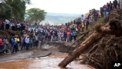 People gather on a bridge where a woman's body was retrieved after floodwater washed away houses and people in Kamuchiri village, Nakuru county, Kenya, on April 30, 2024. At least 48 people were killed in the incident.