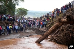 People gather on a bridge where a woman's body was retrieved, after floodwater washed away houses, in Kamuchiri Village Mai Mahiu, Nakuru County, Kenya, April 30, 2024.